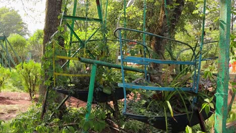 Hanging-Plants-On-The-Old-Swing-Of-Unused-Playground-At-Summer