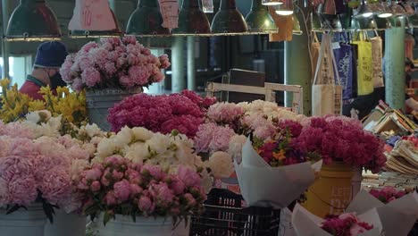 Slow-motion-shot-of-a-beautiful-flower-stall-inside-of-the-famous-tourist-attraction-of-Pike-Place-Market-where-tourists-and-locals-come-to-buy-flowers-in-Seattle,-Washington-USA