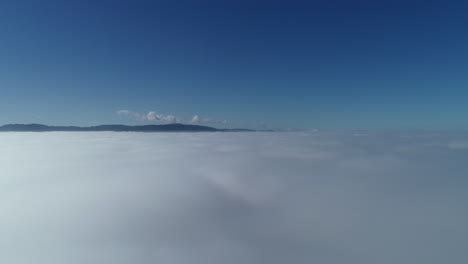 Drohnenakzent-Durch-Weiße-Wolken,-Die-Einen-Wunderschönen-Blauen-Himmel-Und-Sanfte-Hügel-In-Der-Ferne-Enthüllen