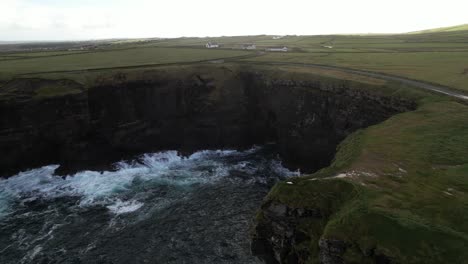 Aerial-View-of-a-Man-Standing-on-a-Top-of-Cliff-at-Irish-Coastline-on-Moody-Day