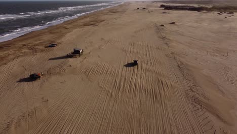 Orbiting-aerial-view-of-car-driving-on-beach