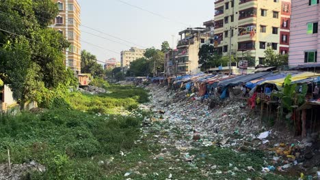 Environment-pollution,-trash-pile-beside-slum-in-urban-city---panning-shot