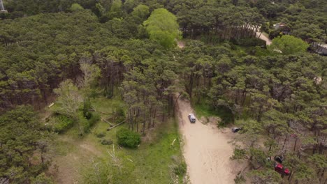 Four-wheel-white-vehicle-driving-on-unpaved-road-in-forest-at-Mar-de-las-Pampas-in-Argentina