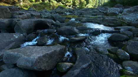 Serene-stream-of-fresh-mountain-water-flowing-through-rocky-stone-riverbed,-New-Zealand