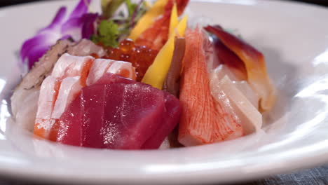 Stunning-assortment-of-colorful-sushi-sashimi-in-white-dish,-Rainbow-chirashi-bowl,-close-up-slider-4K