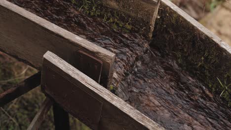 Close-up-of-a-wooden-gutter-with-water-flowing-inside