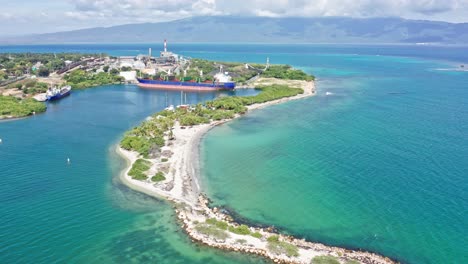 Aerial-shot-showing-port-of-Barahona-with-industrial-ship-docking-surrounded-by-Caribbean-Sea-in-Summer