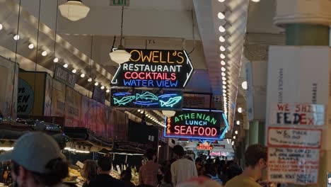 Slow-motion-shot-of-the-famous-neon-signs-inside-of-the-popular-tourist-attraction-Pike-Place-Market-in-Seattle,-Washington-where-people-go-to-buy-goods-and-souvenirs