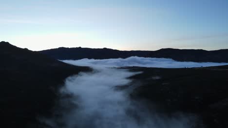 Aerial-view-of-a-beautiful-valley-covered-with-fog-and-clouds-floating