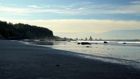 The-beautiful-Third-Beach-in-Forks,-Washington-with-golden-sand,-large-cliffs-with-pine-trees,-and-rock-formations-in-the-water-on-a-warm-sunny-summer-morning