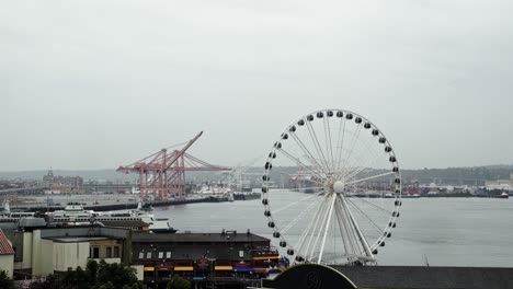 Beautiful-shot-of-the-Seattle-marina-with-the-famous-ferris-wheel-during-an-overcast-cloudy-day-with-a-large-port-in-the-background-in-Washington-State,-USA