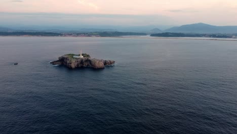 White-Lighthouse-on-lonely-remote-island-near-Spanish-coastline,-aerial-view