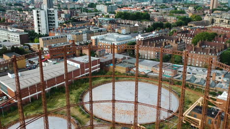 Rusty-Victorian-gas-holder-in-East-London-with-drone-revealing-the-local-Bethnal-Green-skyline-with-residential-buildings