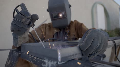 Front-shot-of-welder-working-on-welding-a-metal-object,-protective-equipment