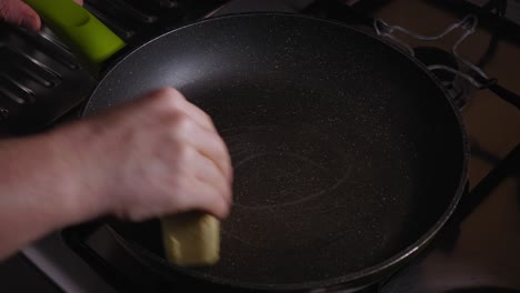 Close-up-View-of-a-Hand-That-is-Applying-Butter-To-a-Frying-Pan---Steady-Shot