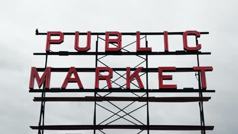 An-isolated-shot-of-the-Public-Market-neon-metal-sign-with-an-overcast-sky-in-the-background-at-the-famous-Pike-Place-market-in-Seattle,-Washington