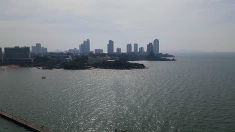 Aerial-footage-of-the-Pattaya-Fishing-Dock-towards-the-Sanctuary-of-Truth-with-buildings-and-beachfronts,-Pattaya,-Chonburi,-Thailand