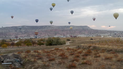 Bunte-Heißluftballons,-Die-Bei-Sonnenaufgang-über-Das-Rote-Tal-In-Kappadokien,-Türkei,-Fliegen---Drohnenaufnahme-Aus-Der-Luft