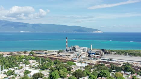 Aerial-view-of-sugar-mill-factory-in-front-of-tropical-Caribbean-Sea-in-background-during-sunny-day---Barahona,Dominican-Republic