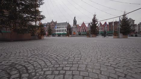 An-early-morning-bicyclist-pedals-across-a-mostly-deserted-Bruges-Christmas-Market-Square