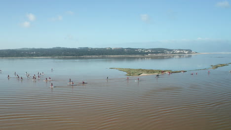 Peaceful-Ocean-With-People-In-Stand-Up-Paddle-Boarding-Wearing-Santa-Claus-Costume-At-Obidos-Lagoon,-Portugal