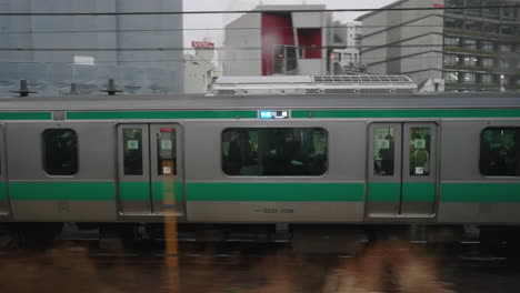 Vista-Desde-El-Lado-De-Un-Tren-Jr-Con-Pasajeros-Moviéndose-En-El-Ferrocarril-En-Tokio