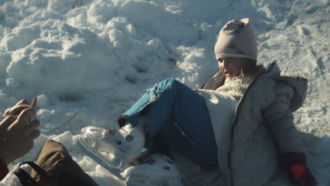 Cute-little-girl-joyfully-ice-skating-and-tumbling-down-on-Lhotka-Frozen-lake-in-Kokorin,-Czech-Republic---Medium-slow-motion-tracking-shot