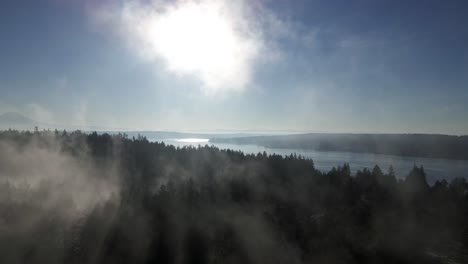 Wisps-of-lingering-fog-burn-away-as-the-sun-reveals-panoramic-Puget-Sound-and-Mount-Rainier,-aerial