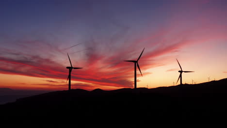 Silhouette-of-Wind-Turbines,-Renewable-Energy,-Mountain-landscape-,-Aerial-View-during-sunset-and-colored-sky
