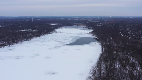 An-aerial-view-from-a-drone,-over-a-frozen-lake-during-sunrise-on-a-cloudy-morning
