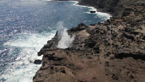 Nakalele-Blowhole,-Maui,-shiny-ocean-water-burst-from-volcanic-rocks-aerial-view