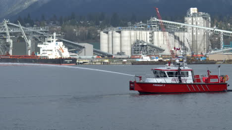 Wide-shot-of-red-fireboat-spraying-water-in-Vancouver-during-daytime