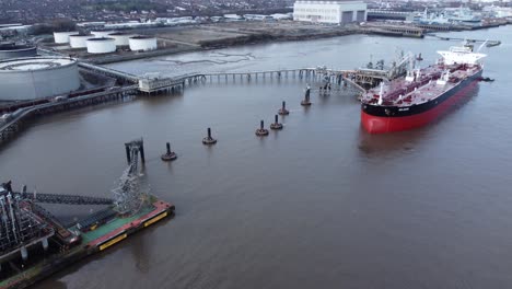 Aerial-view-International-crude-oil-tanker-docked-at-refinery-terminal-pier-facility-pull-back-left
