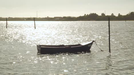 4K-wooden-boat-moored-in-the-Ria-de-Aveiro-in-the-estuary-of-the-river-Vouga,-boat-balancing-in-the-river-current