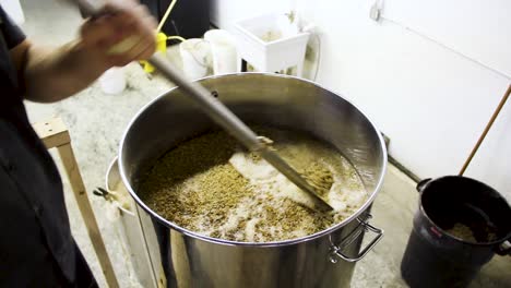 Person-Stirring-Grain-in-Pot-of-Alcoholic-Beer-at-Brewery
