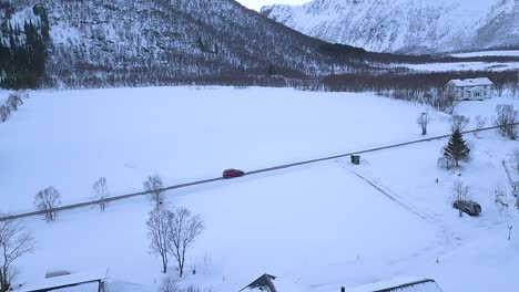 Schwarzes-Auto,-Das-Auf-Der-Straße-Fährt,-Die-Im-Winter-Auf-Der-Insel-Andoya,-Norwegen,-Von-Schnee-Umgeben-Ist