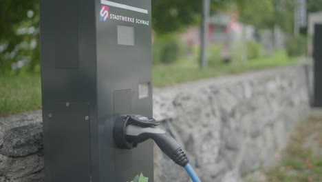 Close-up-of-a-modern-electric-car-charger-station-with-a-charger-being-attached-to-a-silver-chaging-station