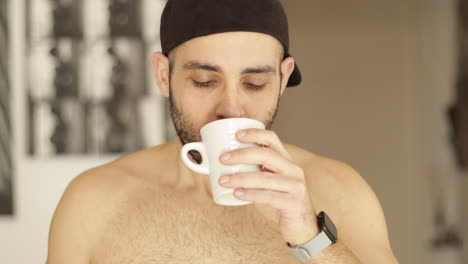 Smiling-caucasian-man-drinks-a-cup-of-tea-or-coffee-indoor