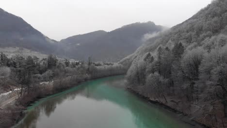 drone-flies-above-beautiful-river-in-winter,-snowflakes-dancing-in-air,-cold-morning