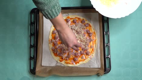 Aerial-view-of-woman-placing-cheese-on-homemade-pizza