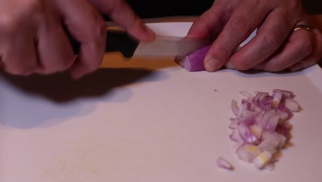 Cutting-onion-with-a-knife-on-wooden-table