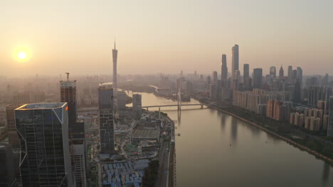 Fly-over-construction-site-of-Alibaba-Group-office-bulding-district-on-bank-of-Pearl-river-at-colorful-golden-sunset-with-Canton-tower-in-far-distance
