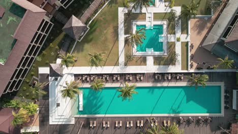 Drone-descending-towards-swimming-pool-in-a-resort,-empty-resort-with-no-people-as-captured-by-drone,-drone-technology-in-the-tourism-sector