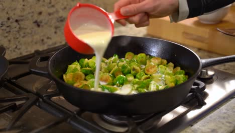 Cooking-Roasted-Sautéed-Brussels-Sprouts-in-a-Cast-Iron-Pan-Skillet---Pouring-Cream-out-of-Measuring-Cup---Wide-Shot
