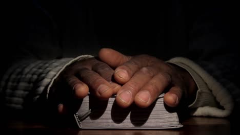 Hombre-Negro-Rezando-Y-Leyendo-La-Biblia-En-Una-Mesa-Almacen-De-Metraje-De-Video