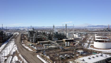 The-aerial-view-moves-up-to-show-a-Refinery-and-highway-with-Downtown-Denver-and-mountains-in-the-background