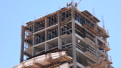 Tilting-Shot-of-Construction-Worker-Lowering-Cement-Bucket-Down-Building-Site