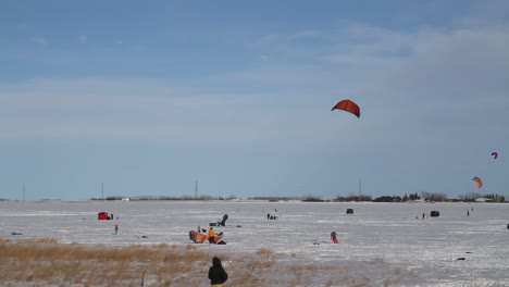 Snowkiter-readies-equipment-and-waits-for-the-inevitable-gust-of-wind-to-start-kite-skiing-across-a-frozen-reservoir-during-a-chinook-winter’s-day-in-Southern-Alberta