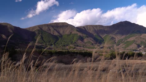 Hermoso-Paisaje-Natural-Con-Hierba-Ondulante,-Montañas-Y-Cielo-Azul-Nublado