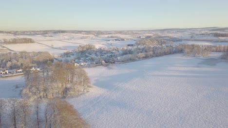 Erstaunliche-Winterlandschaft-Mit-Bäumen-Und-Feldern,-Die-Mit-Weißem-Schnee-Bis-Zum-Horizont-An-Einem-Hellen-Kalten-Tag-In-Schottland-Während-Der-Goldenen-Stunde-Bedeckt-Sind